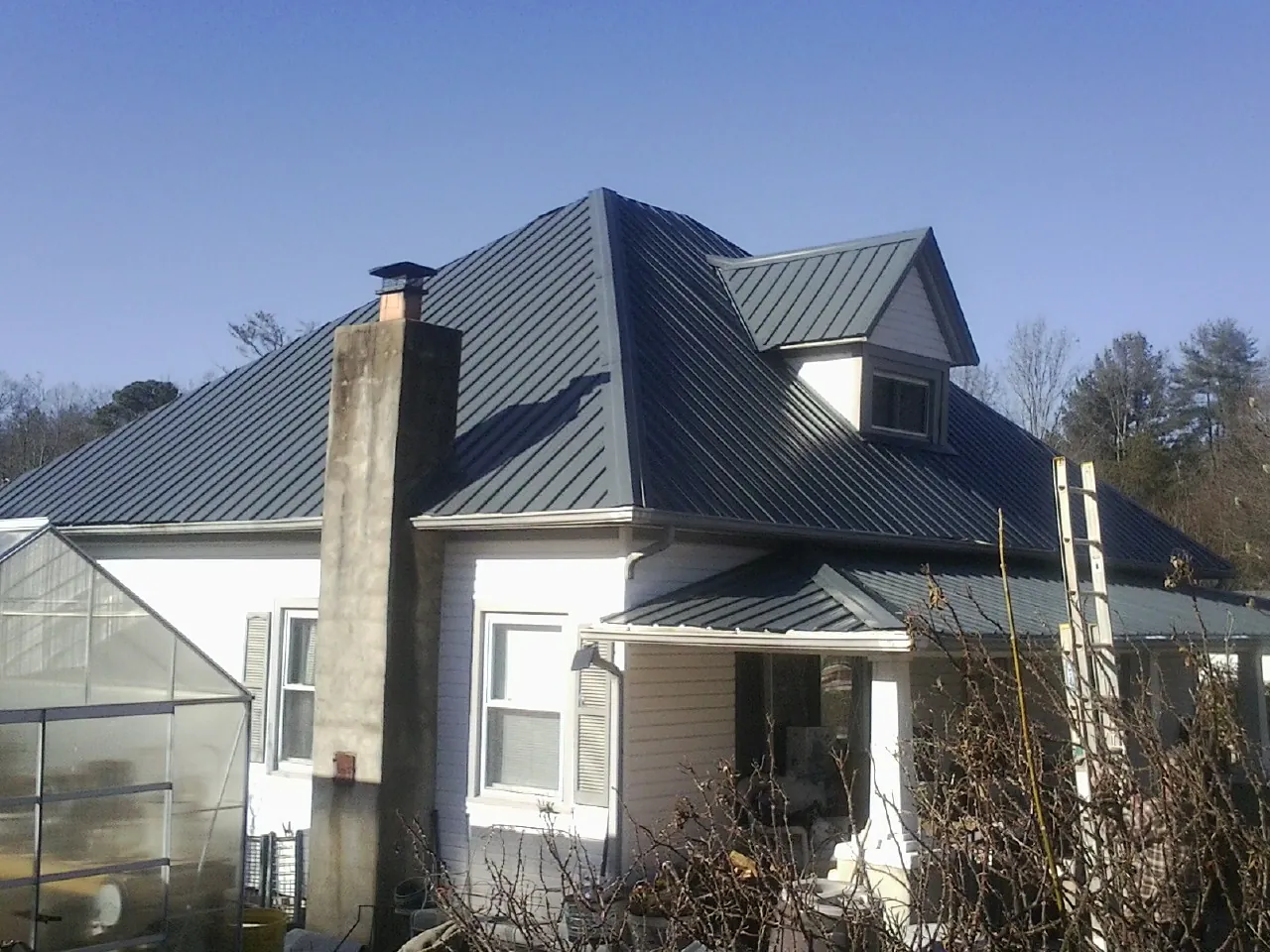 Dark blue standing seam metal roof on a white farmhouse with dormer — Slate & Tile Roof Repair by Roofing Brothers in Lewis Center