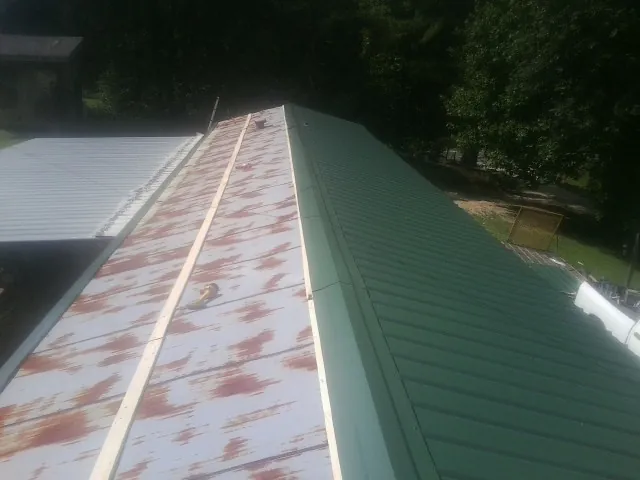 Old rusted panels beside newly installed green metal roofing — Wind Damage Roof Repair by Roofing Brothers in Lewis Center