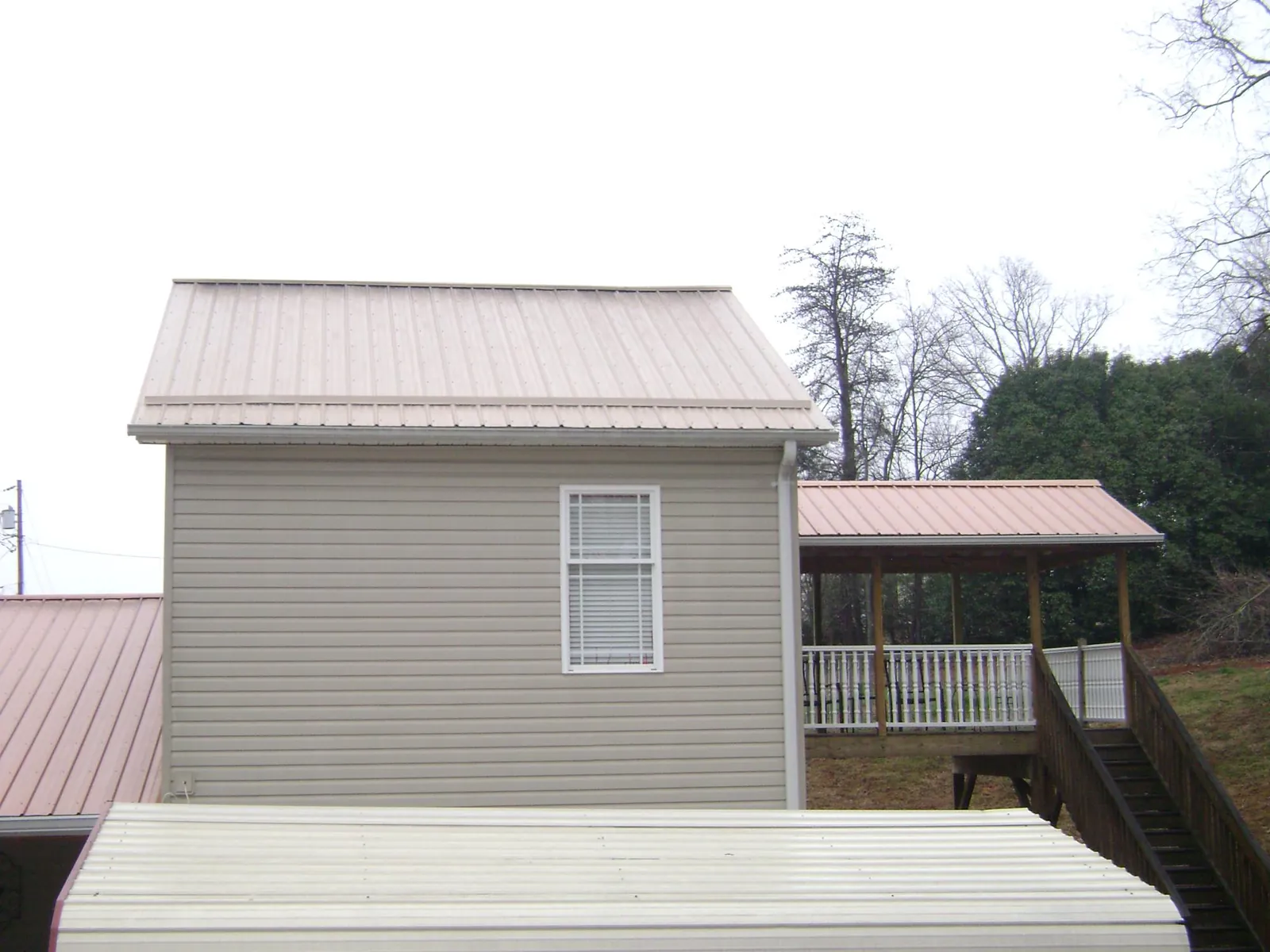 Tan metal roofs on a two story addition and attached porch, from a Roof Replacement job in Lewis Center