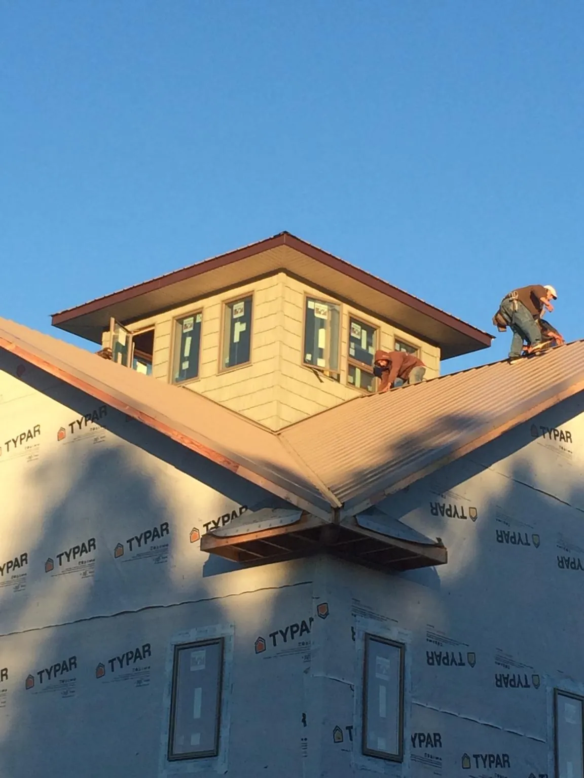 Roofers working around a rooftop cupola on a new metal roof at sunset — Roof Waterproofing in Lewis Center by Roofing Brothers